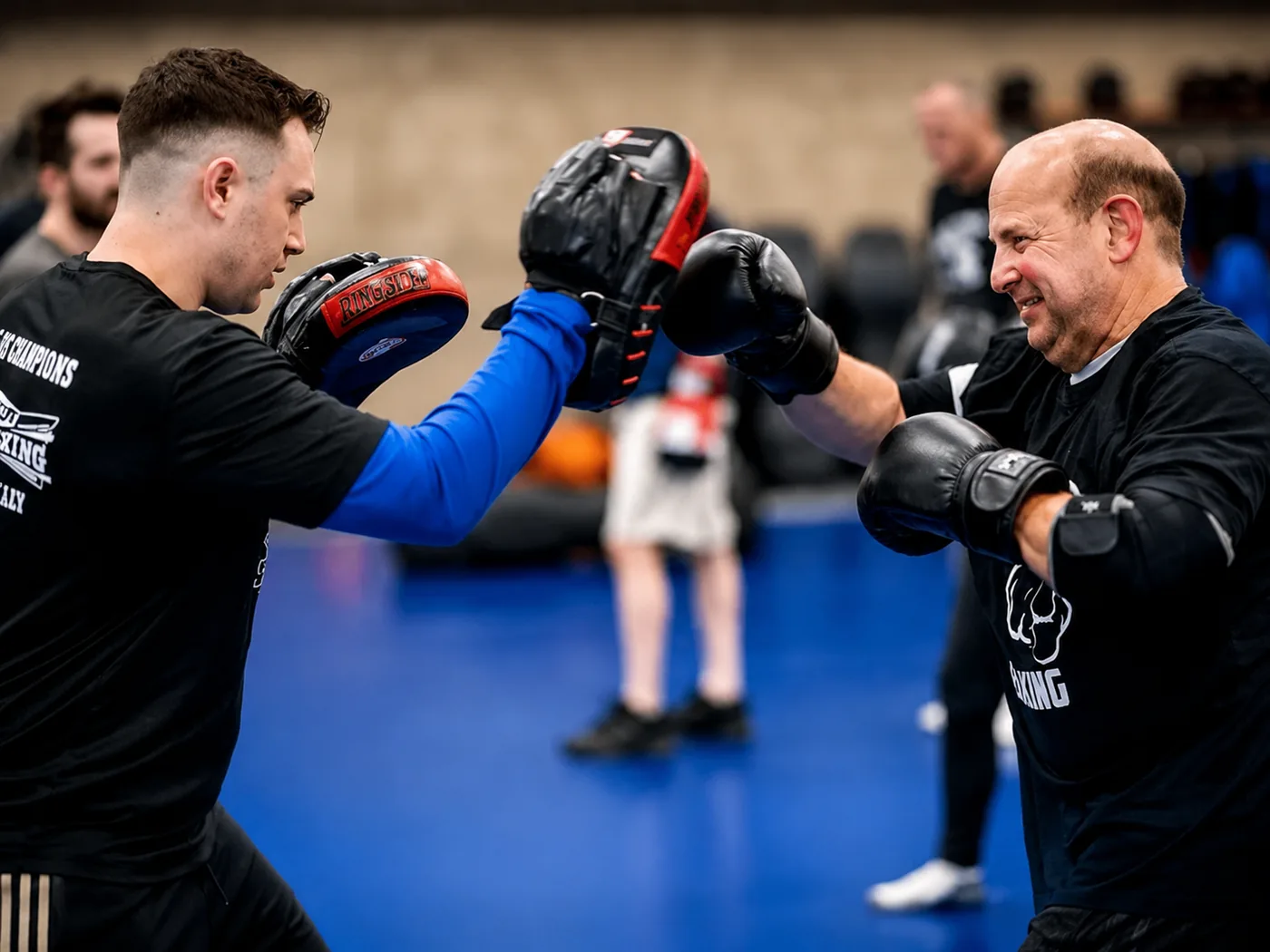 A coach holding focus mitts while a man throws a punch during a Parkinson's boxing class